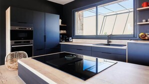 Een moderne keuken met donkere kastjes, een groot raam en een inbouwfornuis.