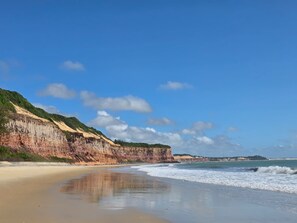 Une plage bordée de falaises, avec une eau calme et un ciel dégagé.
