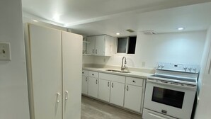 A kitchen with white cabinets, a sink, and a stove. - Amazing apartment in house Basement (Toronto)
