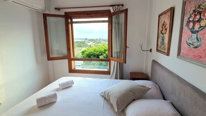 A bedroom with a bed, two towels, a nightstand, a lamp, and a window with curtains. - House 1min steps from the beach and nature, with AC, internet. (Santa Pola)