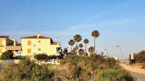 Un bâtiment situé sur la côte, doté de balcons et entouré de palmiers et d’une végétation luxuriante.