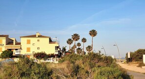 A coastal building with balconies, surrounded by palm trees and dense shrubbery. - House 1min steps from the beach and nature, with AC, internet. (Santa Pola)