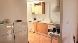 A compact kitchen with a dishwasher, a coffee maker, a toaster, and a stove.