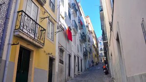 Una estrecha calle adoquinada bordeada por edificios con balcones y puertas, bajo un cielo despejado.