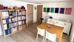 A room with a wooden bookshelf, a dining table with chairs, a white dresser, and a lamp. - Modern, comfortable apartment located 200 meters from the beach and 1 km from shops (Roquebrune-sur-Argens)