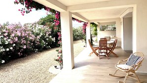 A covered patio with a table and chairs, surrounded by flowering plants. - Modern, comfortable apartment located 200 meters from the beach and 1 km from shops (Roquebrune-sur-Argens)