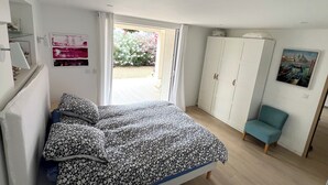A bedroom with a bed, a wardrobe, a chair, and a door leading to a garden. - Modern, comfortable apartment located 200 meters from the beach and 1 km from shops (Roquebrune-sur-Argens)