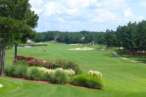 A golf course with a pond, sand bunkers, and a clubhouse in the distance. - 189 Cordero Cottage Ln (Hot Springs)