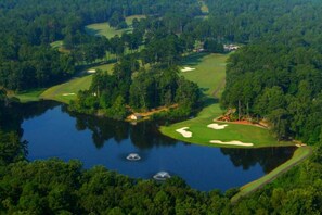 Een golfbaan met waterhindernissen, zandbunkers en een vijver.