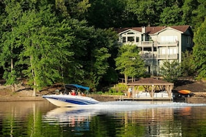 A lake with a boat, docked boats, and a house with a dock. - 189 Cordero Cottage Ln (Hot Springs)