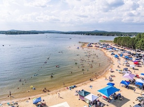 A beach with people swimming and sunbathing, tents, and umbrellas. - 189 Cordero Cottage Ln (Hot Springs)