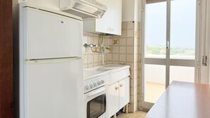 A kitchen with a refrigerator, stove, and oven, a window with a view, and a door leading outside. - SE278 – Senigallia, seafront two-bedroom apartment with balconies and parking space (Senigallia)