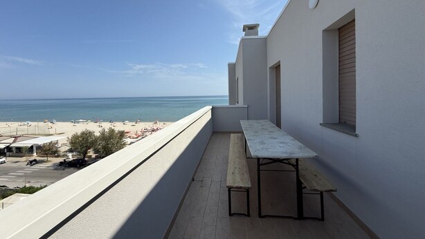 A balcony with a view of the beach and ocean, a table, and a bench. - SE278 – Senigallia, seafront two-bedroom apartment with balconies and parking space (Senigallia)