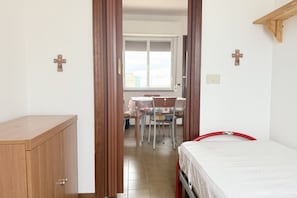 Un dormitorio con cama, un armario de madera y una zona de comedor con sillas y una mesa.