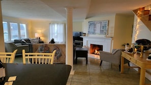 Een woonkamer met een open haard, een eettafel en een bank.