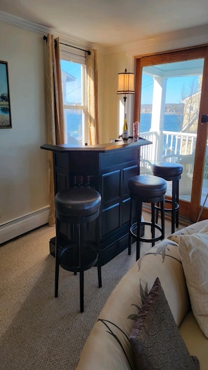 Ein Zimmer mit Bar, zwei Barhocker, einer Couch und Meerblick.