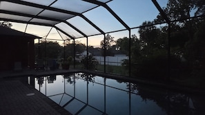 Ein überdachter Außenbereich mit einem spiegelnden Pool, einer Sitzgelegenheit und Blick auf die umliegende Landschaft.