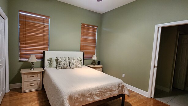 Une chambre à coucher avec un lit, deux tables de chevet, une commode et une porte.