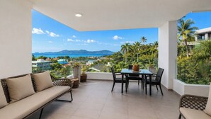 A balcony with a view of a coastal landscape, a table with chairs, and a sofa. - Best Sea Views Walk Surin Beach- Sunsuri C297 (Choeng Thale)