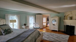 Une chambre à coucher avec un lit, une commode, une chaise et une cheminée.