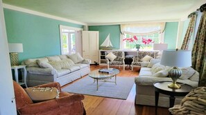 A living room with a sofa, armchairs, a coffee table, and a bookshelf. - Oceanview Classic Maine Cottage within 1 minute. (York)