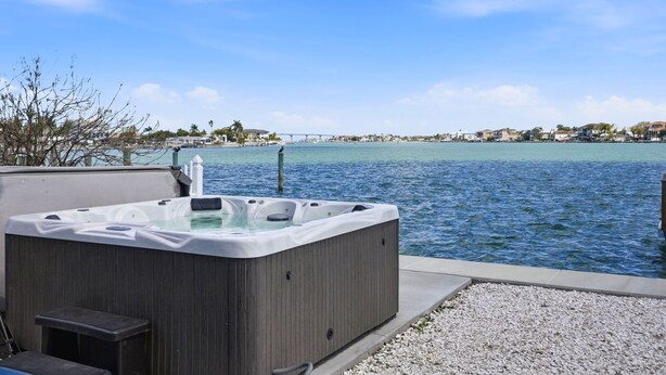 Un jacuzzi frente a la orilla del agua, con un puente al fondo.