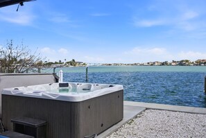 Un jacuzzi frente a la orilla del agua, con un puente al fondo.