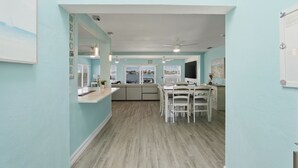 Una cocina con comedor, paredes azul claro y suelo de madera.