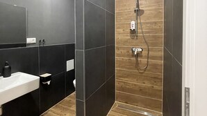 A modern bathroom with a large mirror, a sink, and a shower area. - Apartmenthaus Zeuthen 3 (Zeuthen)