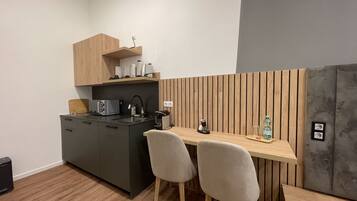 Una cucina moderna con un'isola in legno, due sedie grigie, un piano di lavoro nero e una parete grigia.