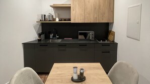 A modern kitchen with a wooden table and chairs, a microwave, and a coffee machine. - Apartmenthaus Zeuthen 3 (Zeuthen)