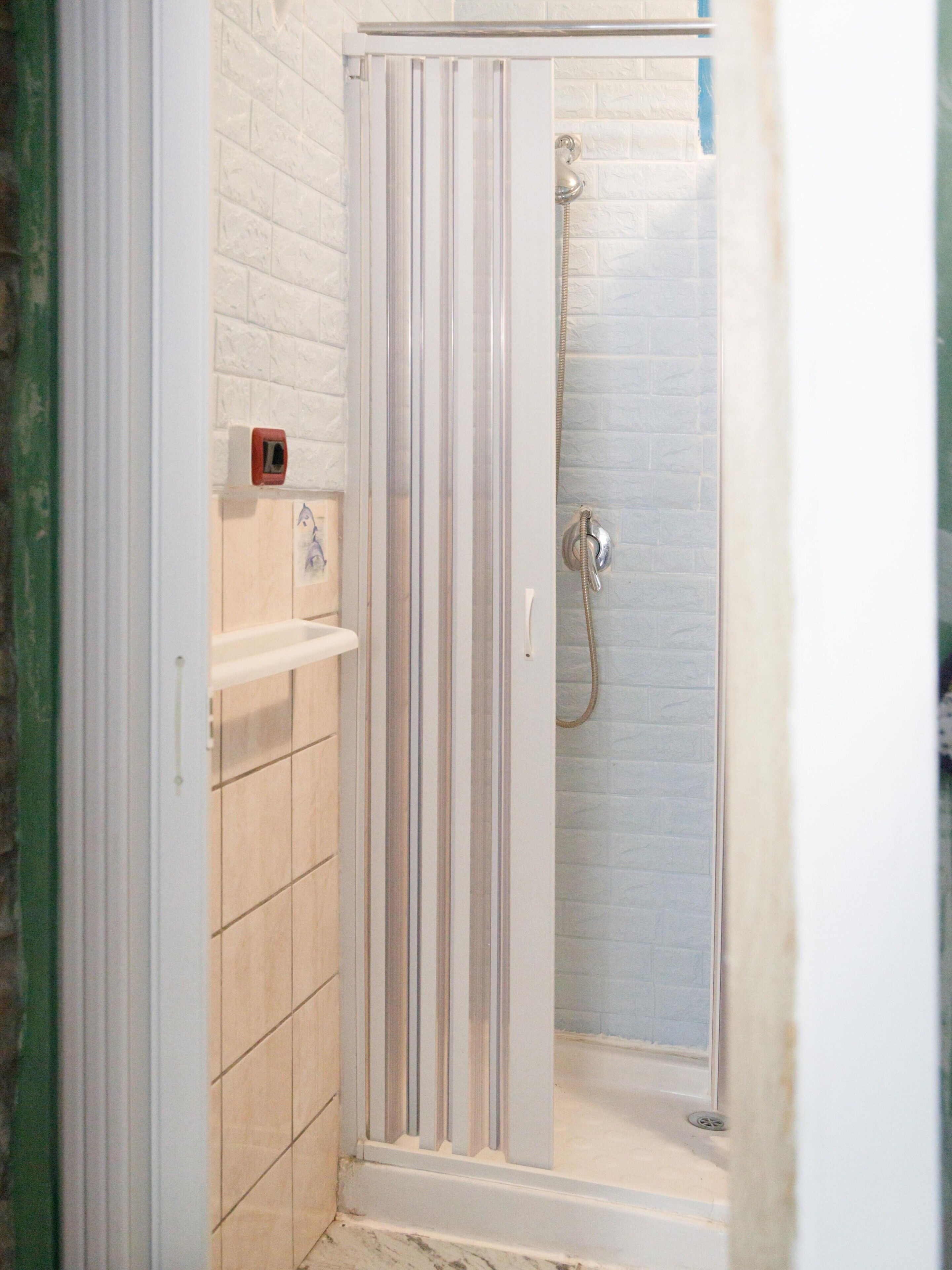 Una ducha con puerta de vidrio, un perchero para toallas y un dispensador de jabón.