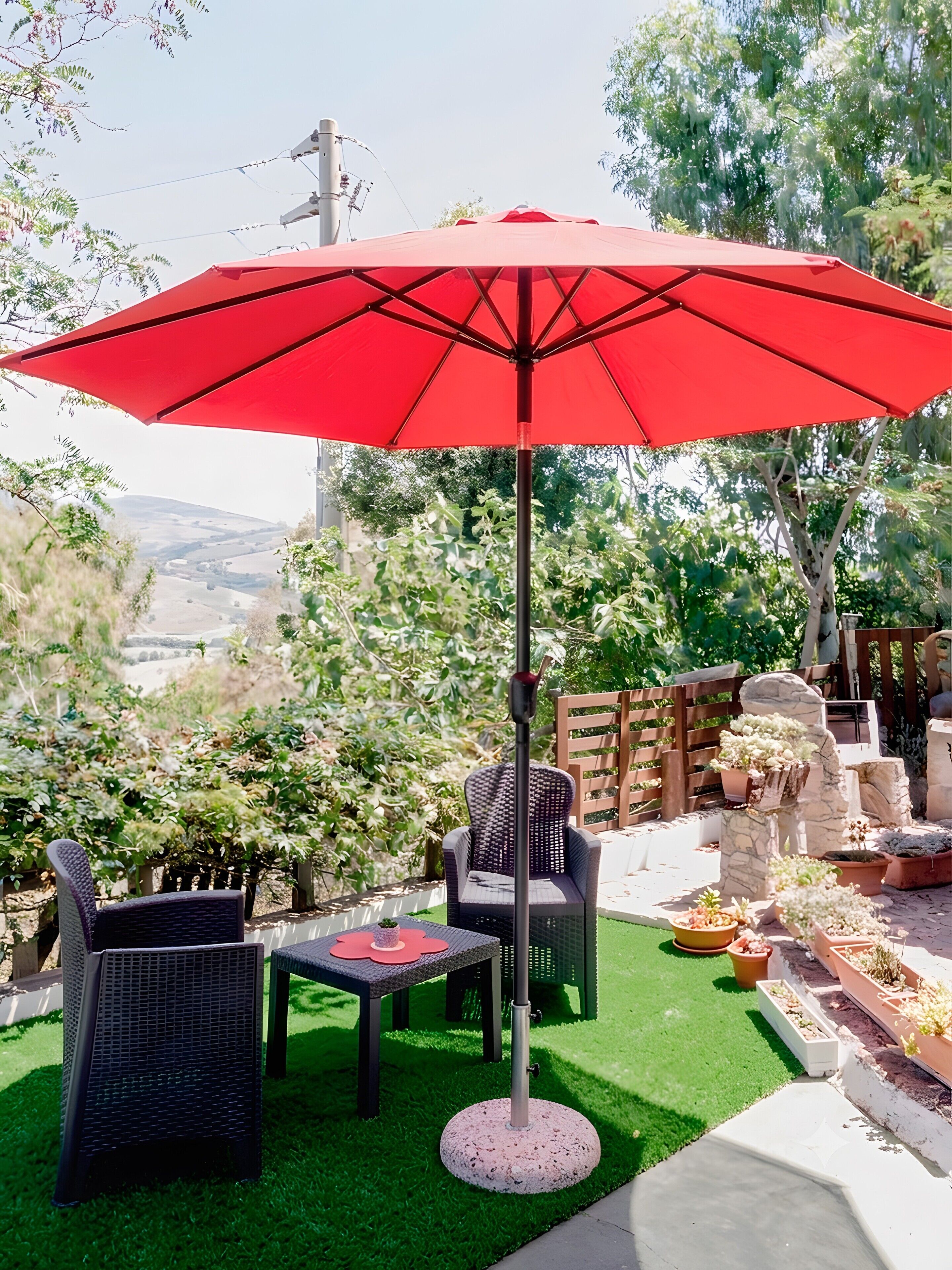 A patio with a red umbrella, wicker furniture, and potted plants.