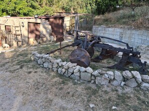 Un espacio al aire libre con un muro de piedra, una estructura metálica y un banco de madera.