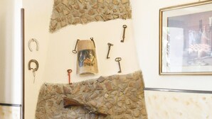 Une cheminée en pierre avec un manteau de cheminée, entourée de murs en pierre et dotée d’un sol carrelé.