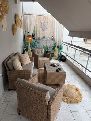 Ein Balkon mit Korbmöbeln, einem Tisch und Zierpflanzen.