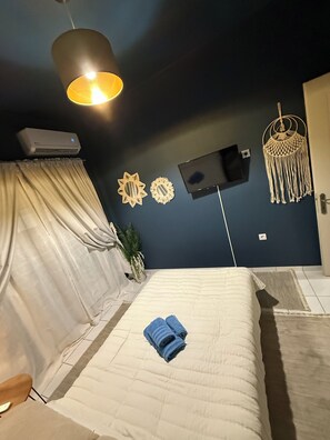 Ein Schlafzimmer mit einem Bett, einem Fernseher, einer Wandklimaanlage und einem Wandbehang aus Makramee.