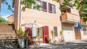En boligbygning med balkon, et bord med stole og plantekasser.
