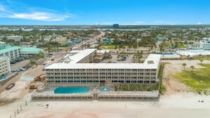 Et stort hotel med flere etager, en swimmingpool og en strand.