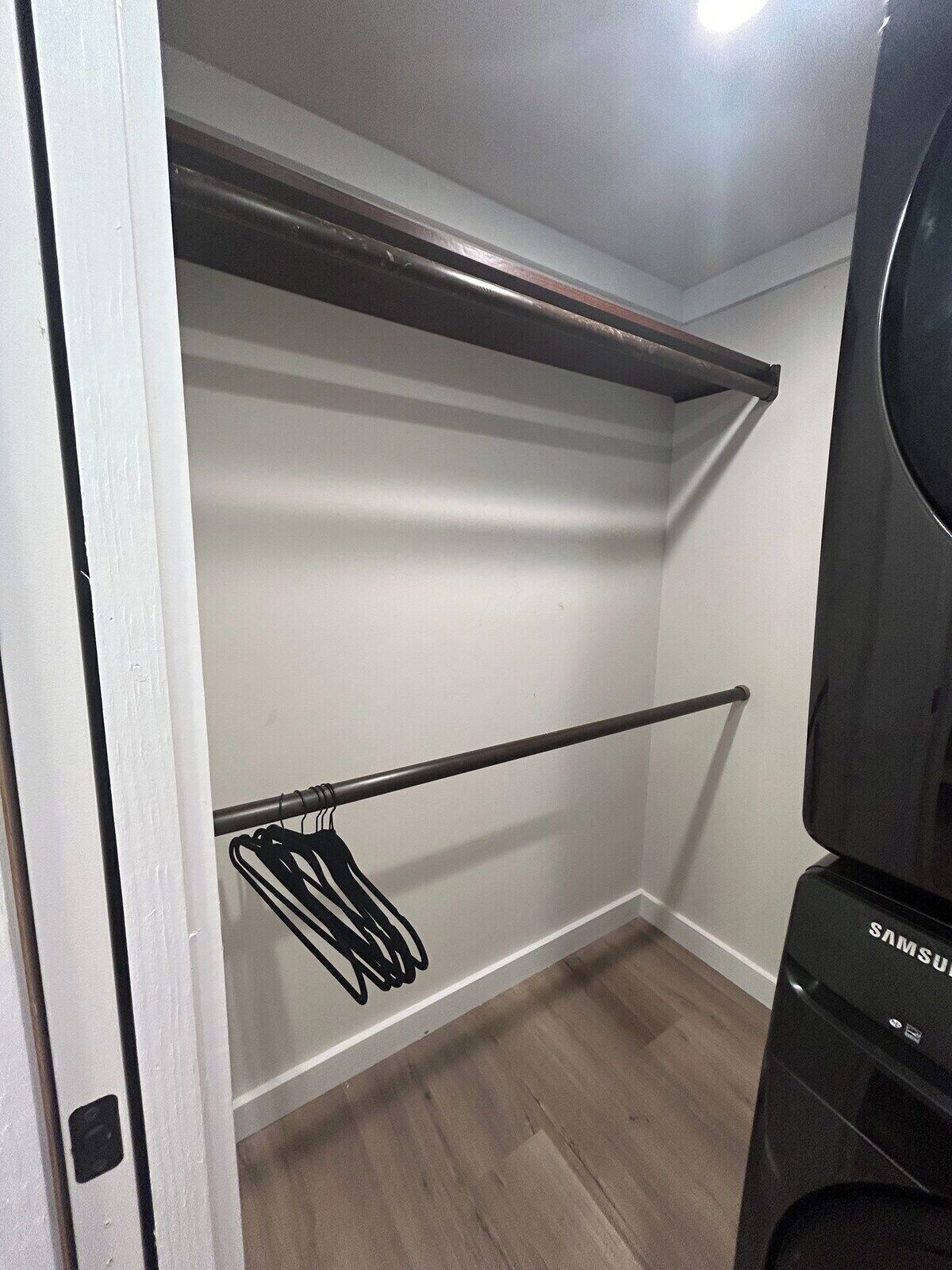A closet with a rod, a hanging rack, and a Samsung appliance.