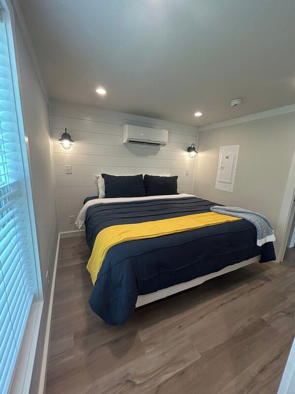 A bedroom with a bed, an air conditioning unit, and a wall-mounted light fixture.