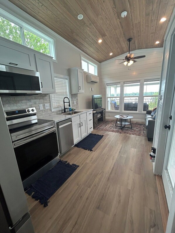 A modern kitchen with a wood ceiling, built-in appliances, and a view to a balcony.
