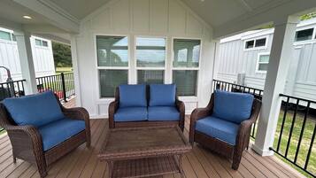 A covered patio with wicker furniture and a central table.