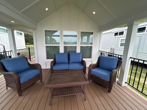 A covered patio with wicker furniture and a central table.