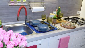 Una cocina moderna con un lavamanos de acero inoxidable, una estufa a gas y diversos utensilios de cocina.