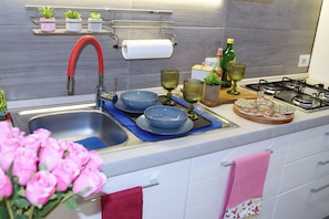 A modern kitchen with a stainless steel sink, a gas stove, and a variety of kitchenware.