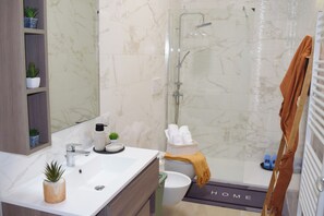Un baño con ducha, inodoro, lavabo y un perchero para toallas.