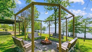 Een houten gazebo met een vuurplaats in het midden, omringd door bankjes.