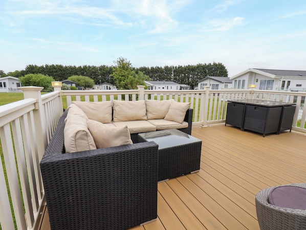 A deck with a wicker sofa and a table, surrounded by a white fence. - Finch 66 (Scarborough)