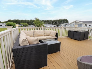 A deck with a wicker sofa and a table, surrounded by a white fence. - Finch 66 (Scarborough)